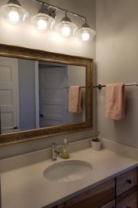 A guest bathroom sink with a large mirror hanging above.
