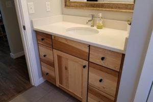 A chestnut bathroom sink cabinet with granite counter.