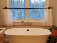 A large tub over looking the front yard through a window.