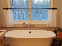 A large tub over looking the front yard through a window.