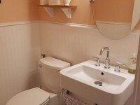 A guest bathroom sink with a round mirror hanging above.
