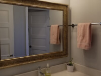 A guest bathroom sink with a large mirror hanging above.