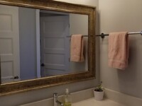 A guest bathroom sink with a large mirror hanging above.