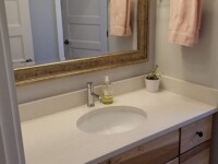 A guest bathroom sink with a large mirror hanging above.