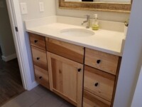 A chestnut bathroom sink cabinet with granite counter.