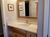 A guest bathroom sink with a large mirror hanging above.