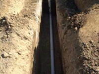 A PVC pipe laid in a long trench in the ground.
